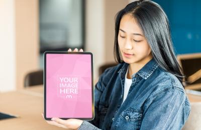 Young Woman Holding and Looking at iPad Mockup 